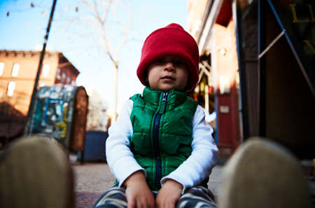 Portrait of male toddler sitting on street sidewalkの写真素材