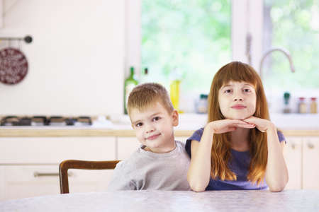 Portrait of sister and brother sitting at kitchen tableの写真素材