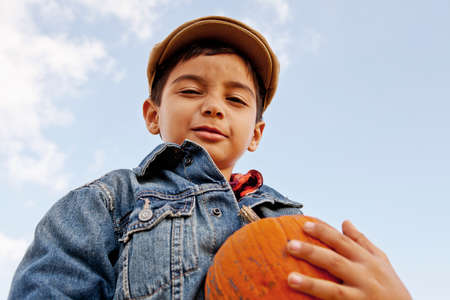 Low angle portrait of boy holding pumpkin