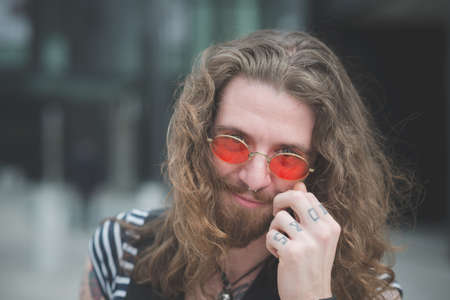 Portrait of young male hippy with orange sunglasses and tattooed fingersの写真素材