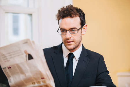 Young businessman reading morning newspaper at home