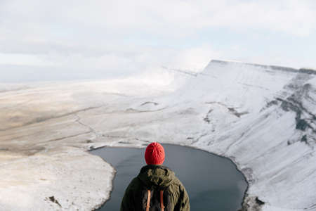 Rear view of man looking at Llyn y Fan Fach, The Brecon Beacons, Wales, UKの写真素材