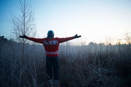 Man with arms open in sunlit rural winter scene
