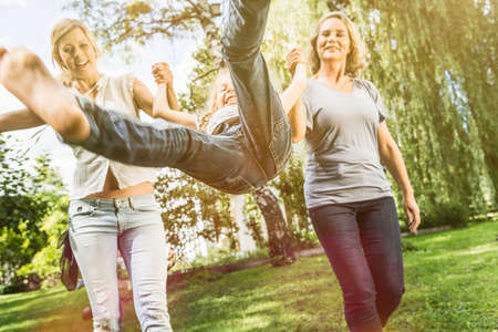 Girl being swung by mother and grandmotherの写真素材