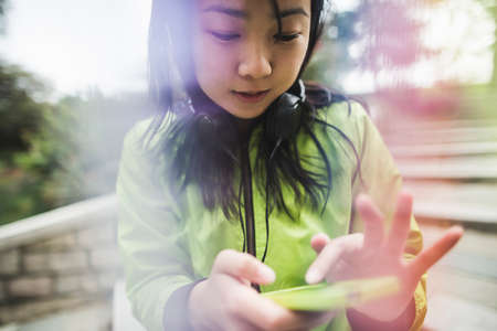 Young woman using mp3 player, wearing headphones, outdoors