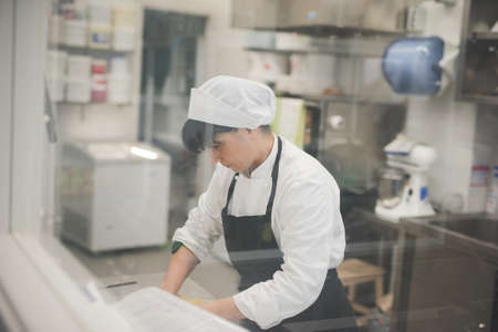 Baker rolling dough in kitchen