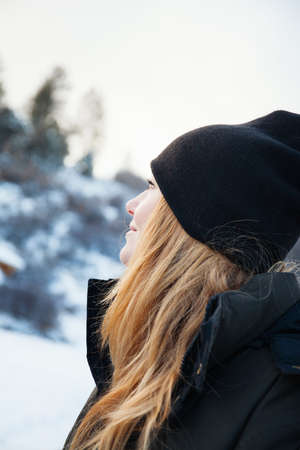 Mid adult woman in knit hat gazing up at snowy landscape