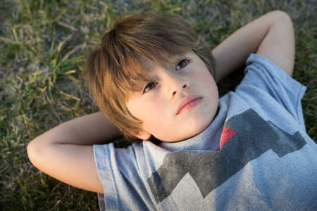 Portrait of boy lying on park grass gazing up