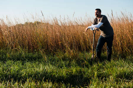 Portrait of mid adult male farmer leaning on spade in field, Plattsburg, Missouri, USA