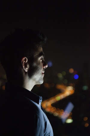 Close up of young businessman looking out of skyscraper office window at night, Shanghai, China