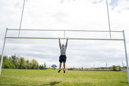 Young man hanging from rugby postの写真素材