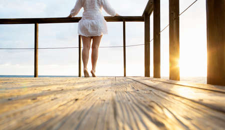 Surface level view of mature woman on tiptoe watching sunrise from balcony, Spanish River Park, Boca Raton, Florida, USAの写真素材