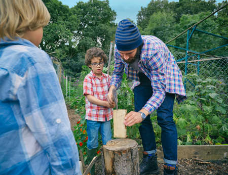 Father explaining how to chop logs to sons