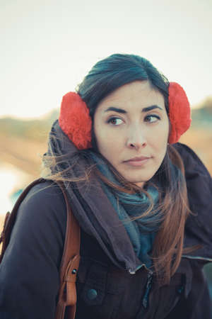 Mid adult woman wearing red ear muffs in park