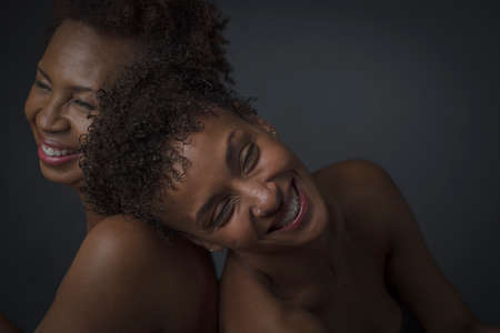 Studio portrait of two mature women laughing back to backの写真素材