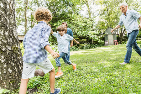 Mid adult man and father playing garden soccer with sons
