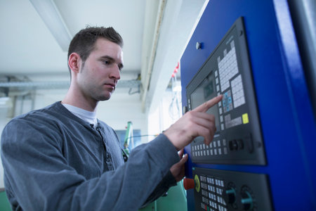 Young male technician using control panel for equipment in workshopの写真素材