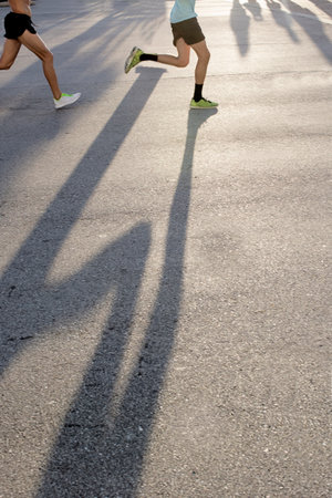Legs of two mature male runners on road runの写真素材