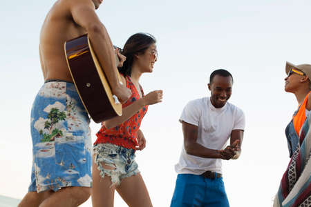 Group of friends singing and playing guitar on beach