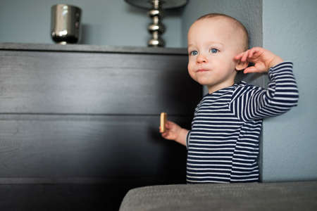 Baby boy eating biscuit in living room