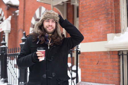 Young man strolling along street drinking takeaway coffee