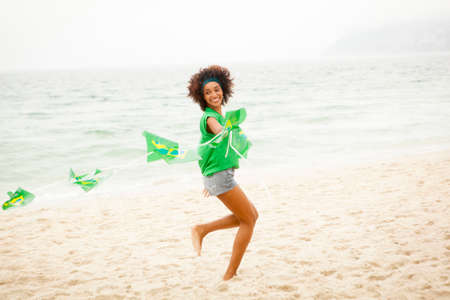 Young woman playing with string of flags on beach, Rio de Janeiro, Brazilの写真素材