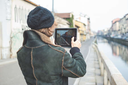 Man taking photograph of canal with digital tablet, Milan, Italy