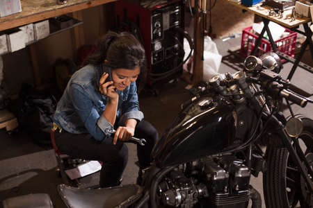 Female mechanic using mobile phone in workshopの写真素材