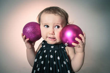 Little girl with pink christmas baublesの写真素材