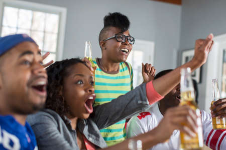 friends partying watching and cheering sports on TVの写真素材