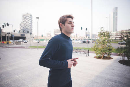 Young male runner running in city squareの写真素材
