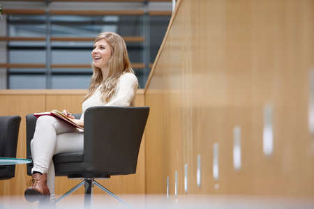 Businesswoman taking notes at conference room meetingの写真素材