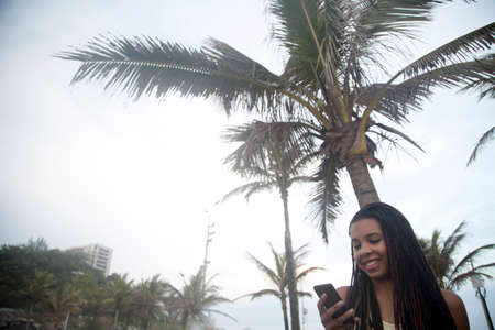 Young women reading smartphone texts on Ipanema beach, Rio De Janeiro, Brazil