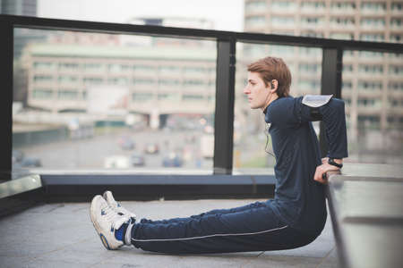 Young man doing reverse push ups on city rooftopの写真素材