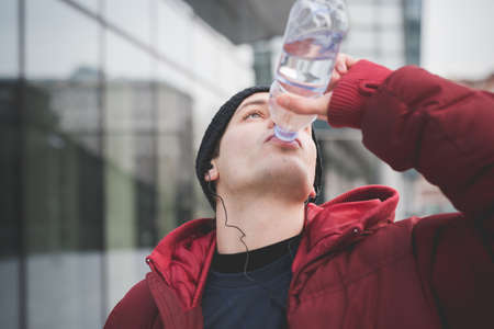 Young man drinking water outside city office