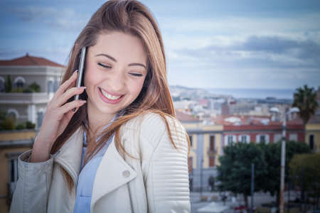 Young woman on rooftop chatting on smartphone, Cagliari, Sardinia, Italyの写真素材