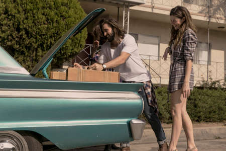 Young couple packing vintage car boot for road trip