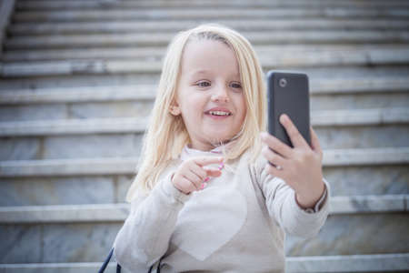 Young girl on stairway taking smartphone selfie, Cagliari, Sardinia, Italyの写真素材