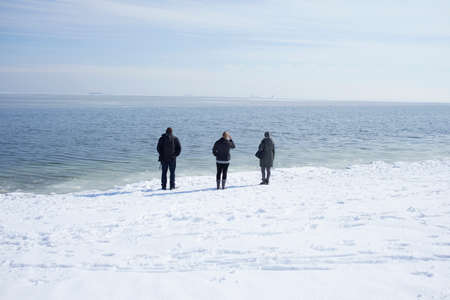 Three adults looking out to sea, Fairfield, Connecticut, USAの写真素材