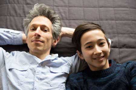 Overhead portrait of teenage boy and father lying back