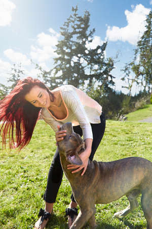 Young woman petting her dog in park