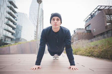 Young male runner doing push ups in cityの写真素材