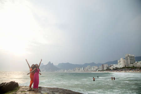 Portrait of two young women with arms raised on Ipanema beach, Rio De Janeiro, Brazilの写真素材