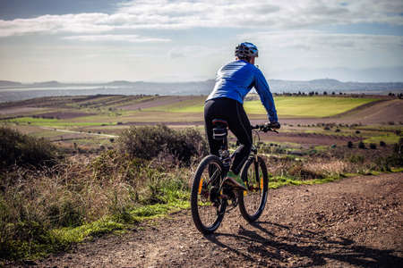 Male mountain biker cycling down dirt track, Cagliari, Sardinia, Italy