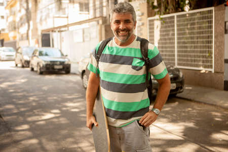 Portrait of mature man carrying skateboard, Rio De Janeiro, Brazilの写真素材