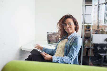Portrait of young woman using digital tablet at office desk
