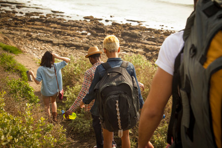 Group of friends walking down towards beach, rear viewの写真素材