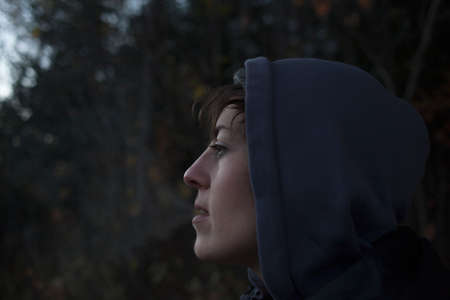Close up portrait of mid adult woman gazing from forest at dusk