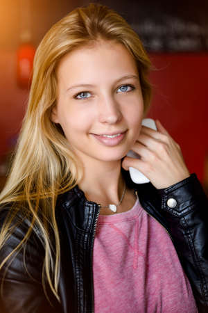 Portrait of young woman holding smartphone in cafe