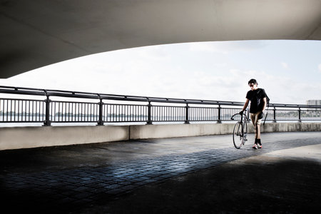 Bike messenger walking, pushing bikeの写真素材